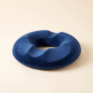 Memory foam donut seat cushion in navy blue on a cream studio background