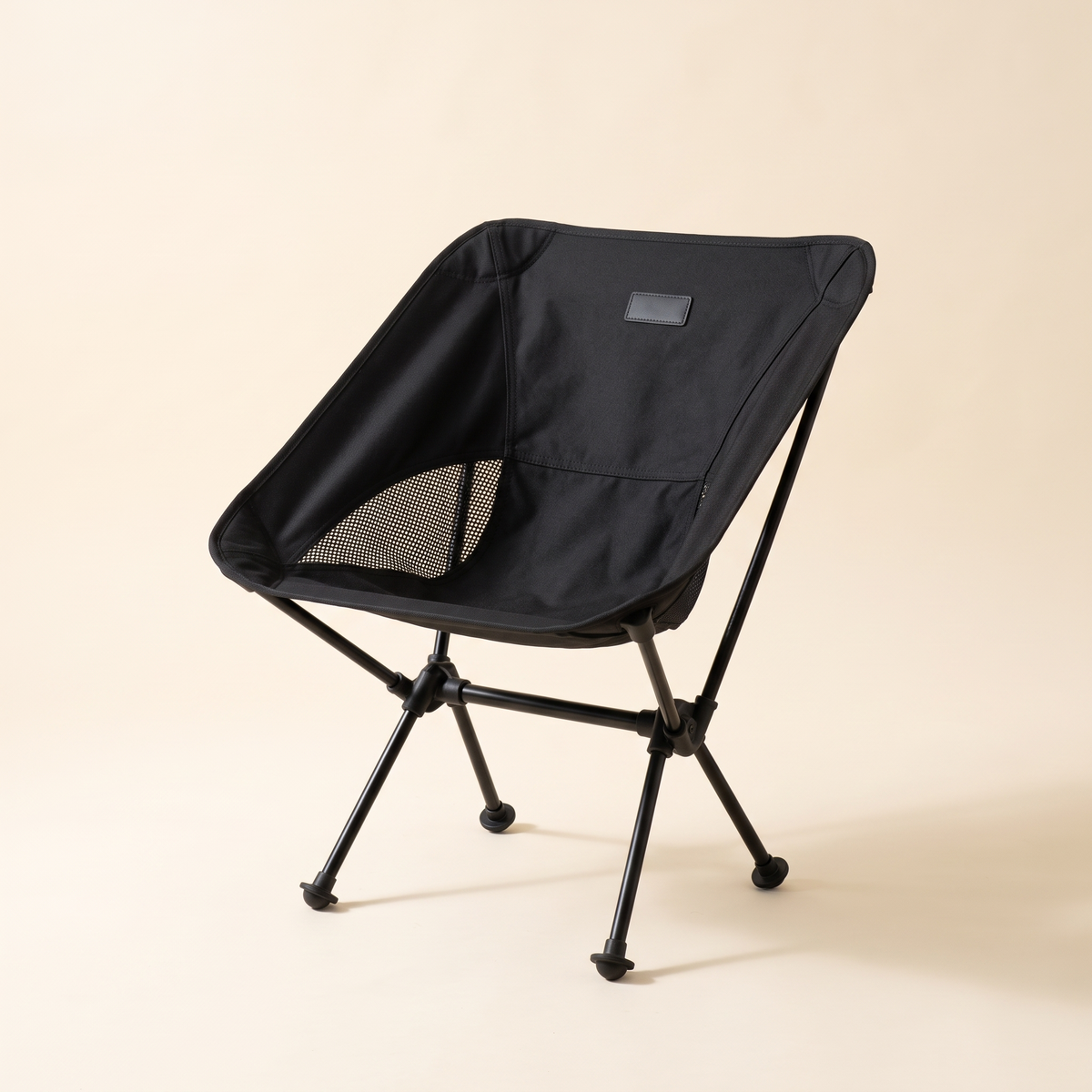Compact folding camping chair in black on a cream studio background