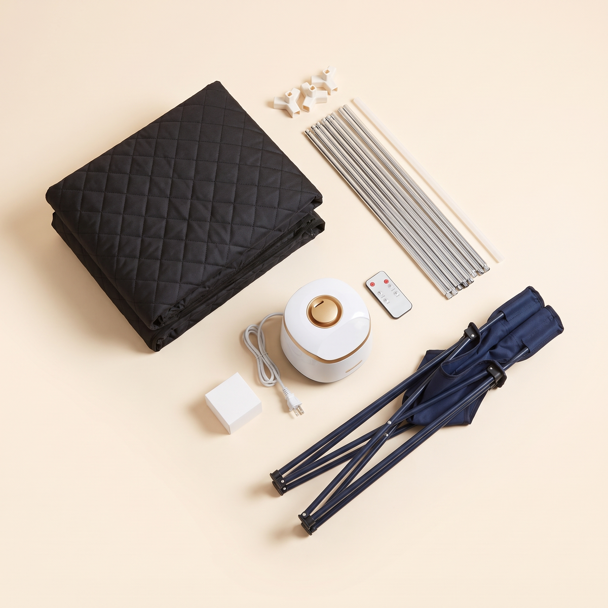 Flat lay of the portable steam sauna kit contents including folded tent, support poles, steamer, remote and chair