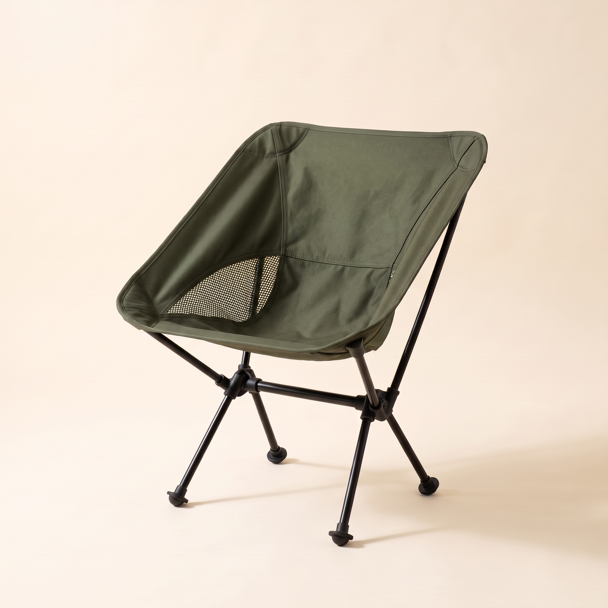 Compact folding camping chair in olive on a cream studio background
