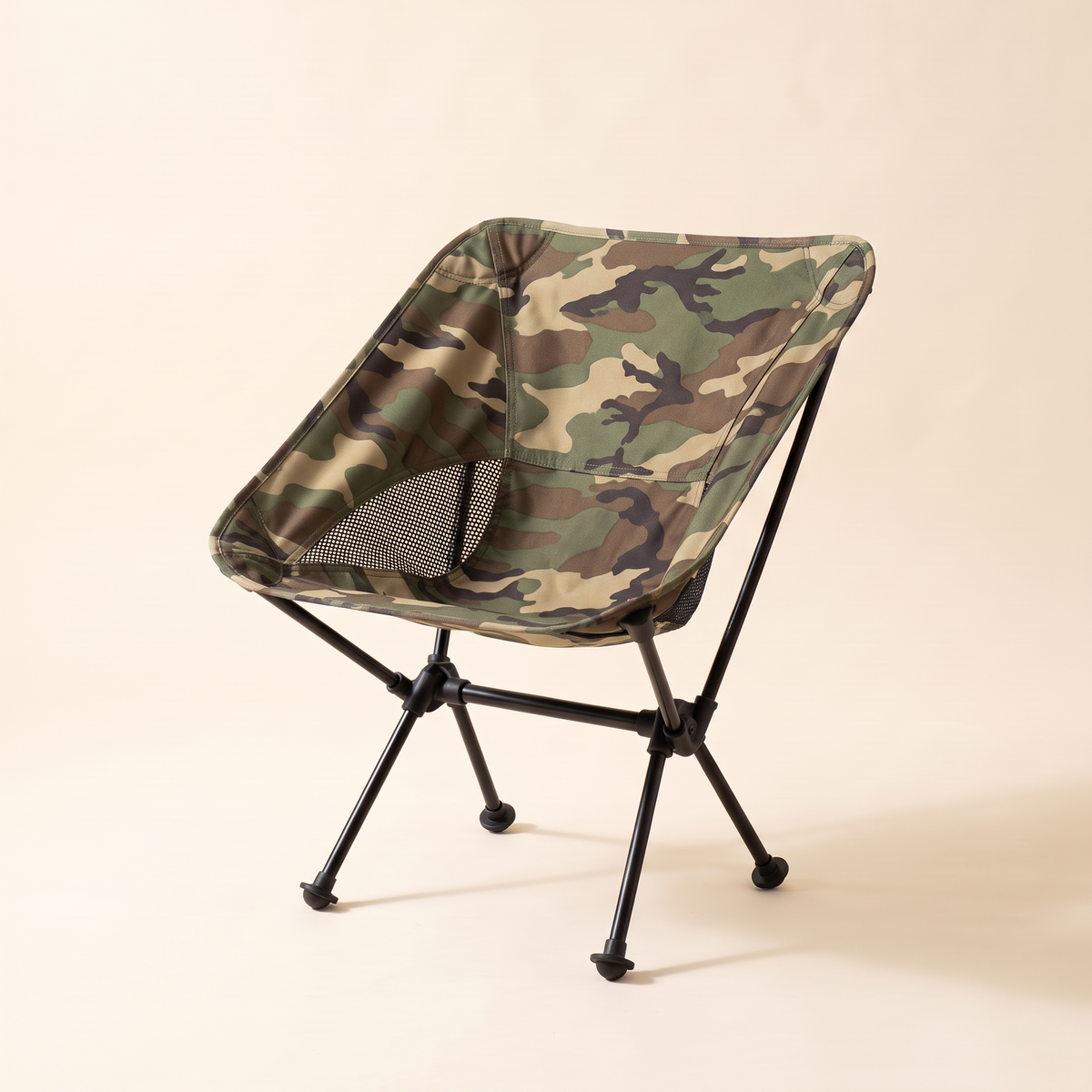 Compact folding camping chair in camo on a cream studio background