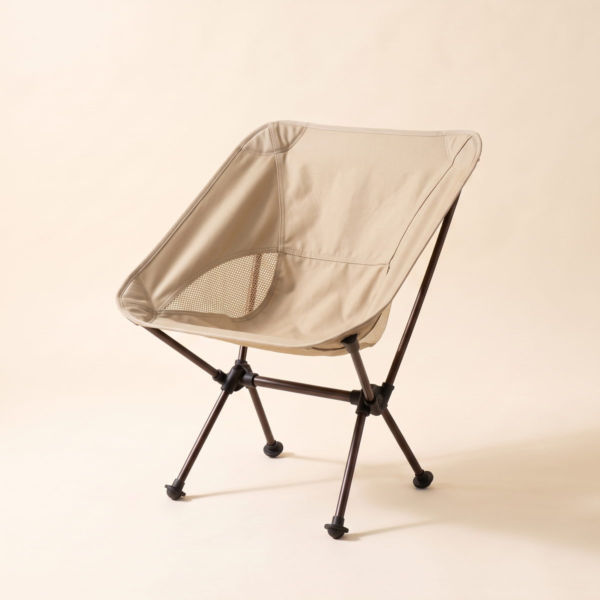 Compact folding camping chair in khaki on a cream studio background