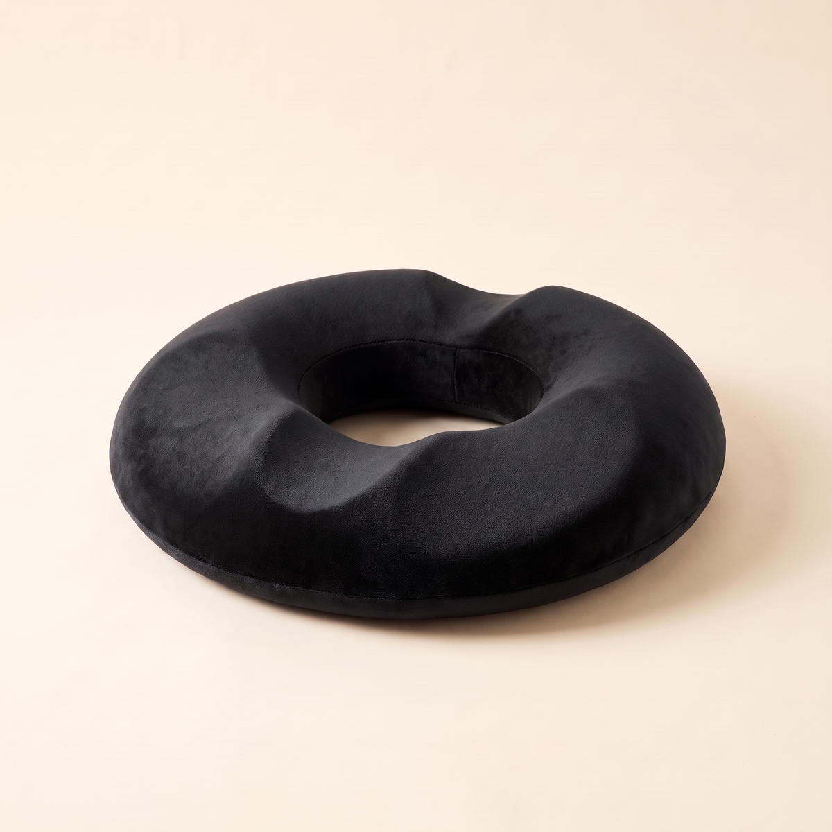 Memory foam donut seat cushion in black on a cream studio background