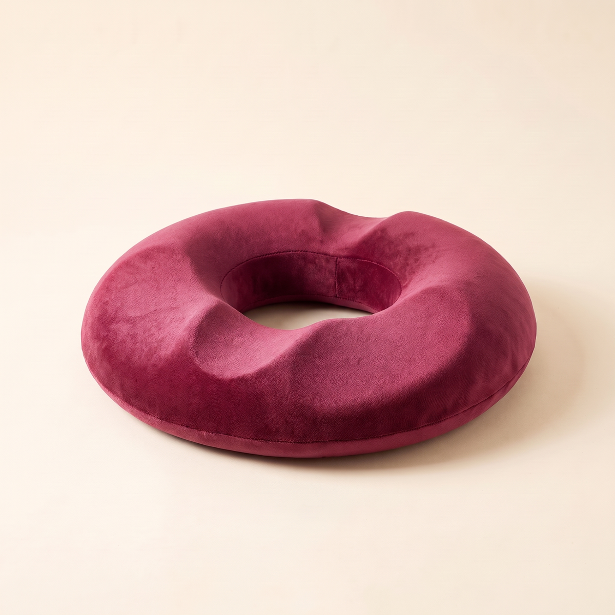 Memory foam donut seat cushion in rose on a cream studio background