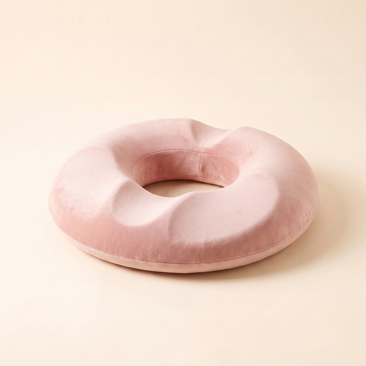 Memory foam donut seat cushion in pink on a cream studio background