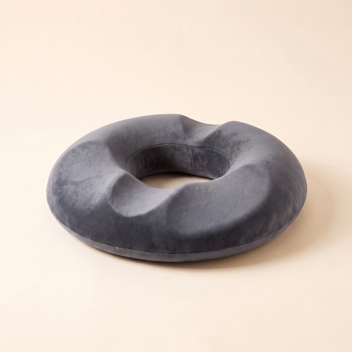 Memory foam donut seat cushion in gray on a cream studio background