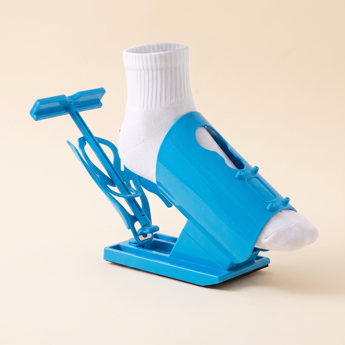 Blue sock puller assist aid with a white sock on a cream studio background