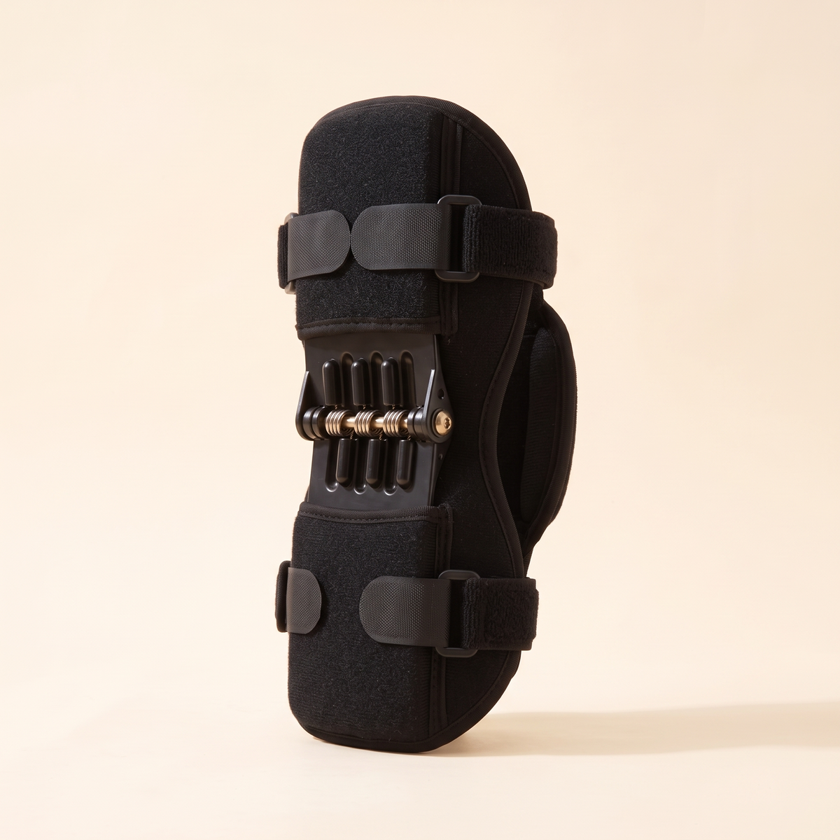 Single black spring support knee brace on a cream studio background