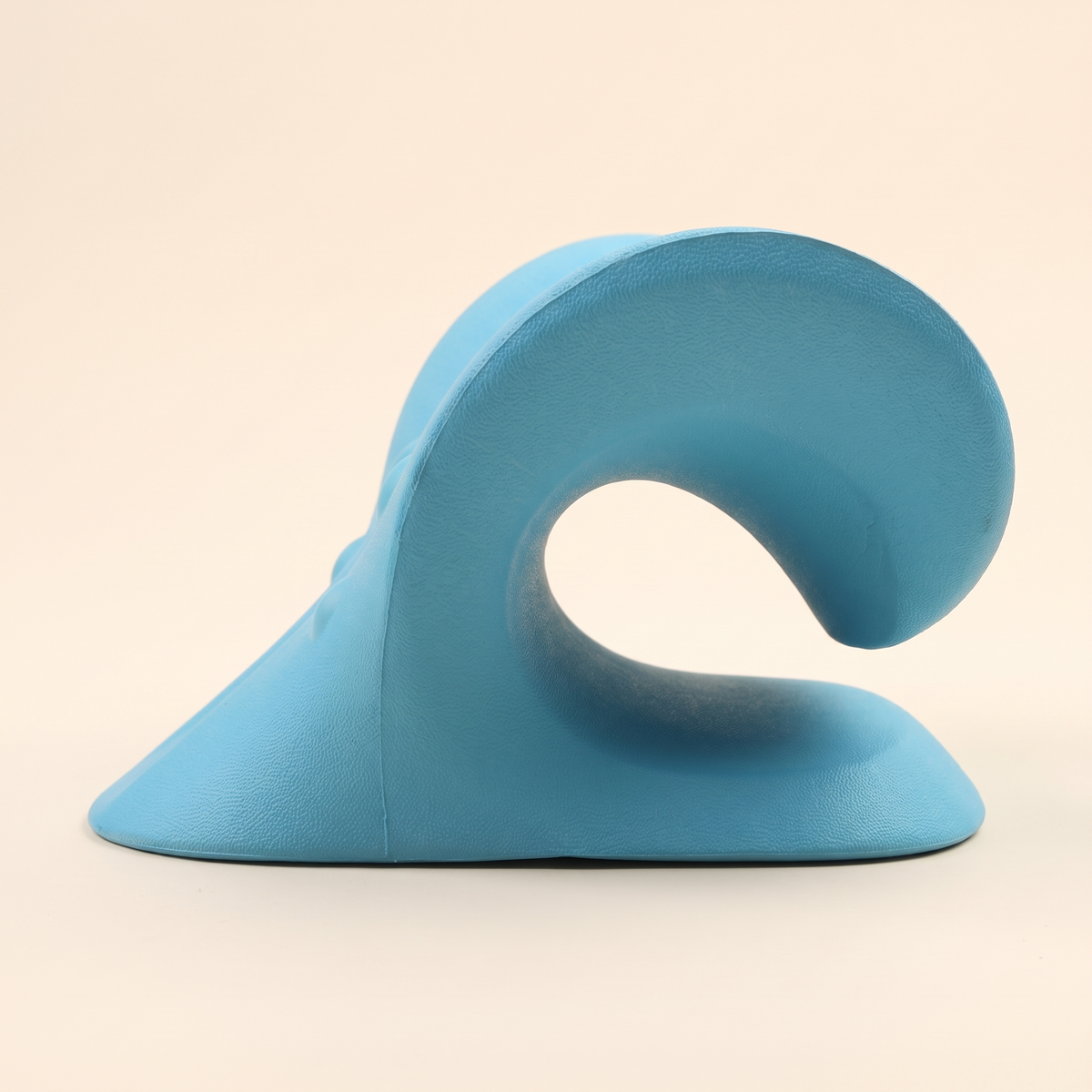 Side profile of the blue C shaped cervical pillow showing the curve