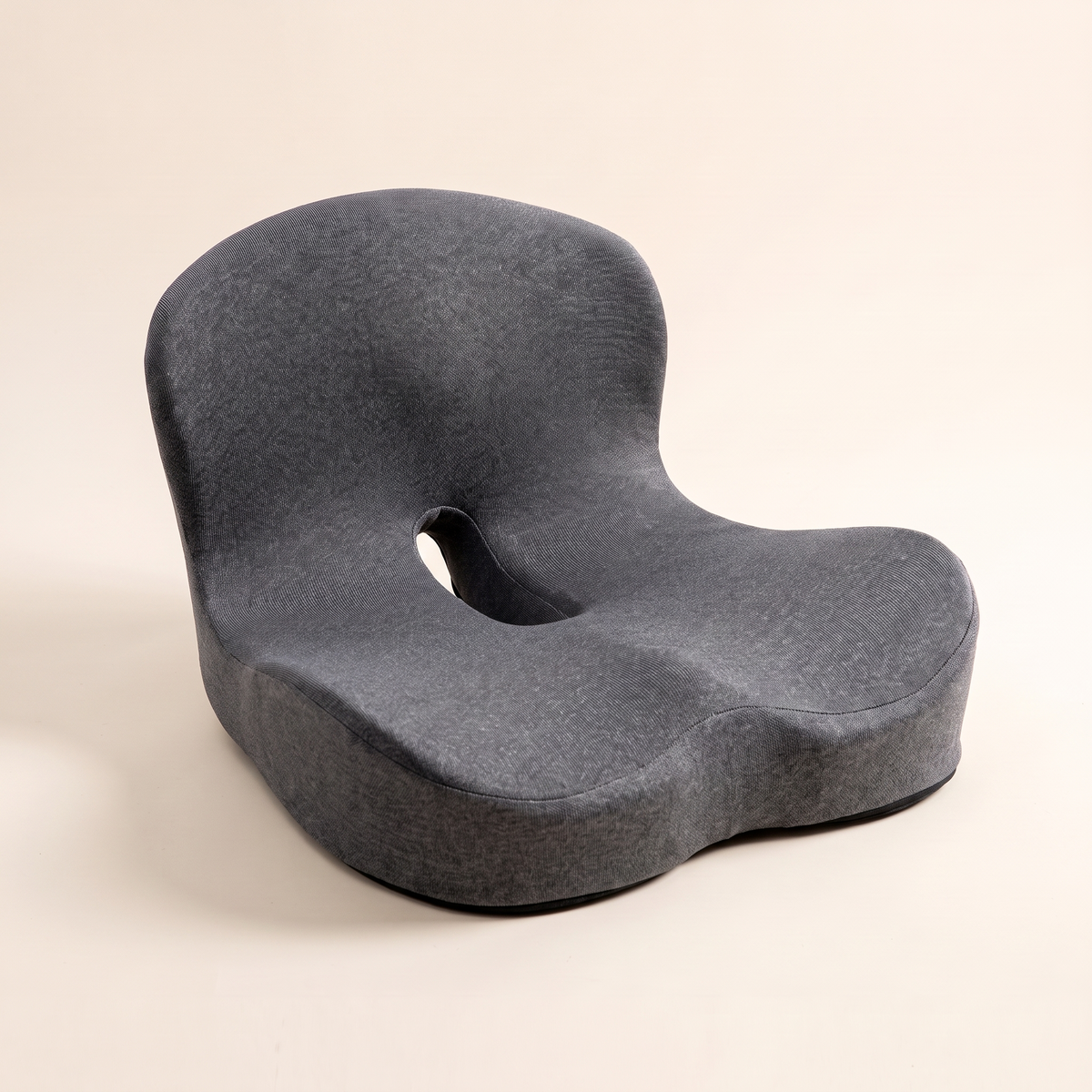 Ergonomic memory foam seat cushion in dark gray knit on a cream studio background