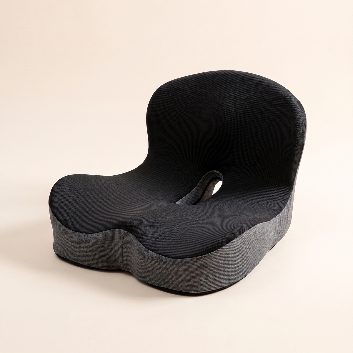 Ergonomic memory foam seat cushion in color blocked black knit on a cream studio background
